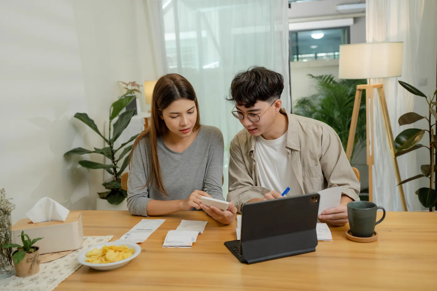 Young couple contemplating finances at their kitchen table.