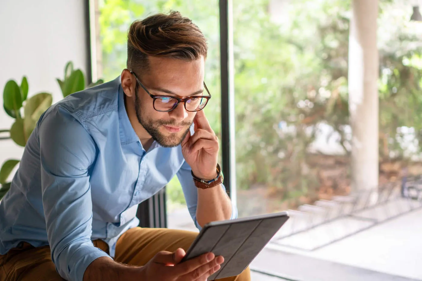 Young smiling man looking at digital tablet.