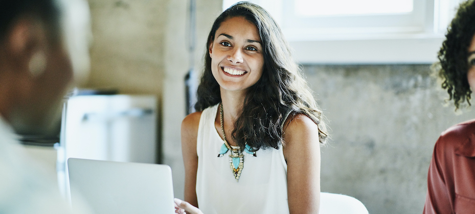 Smiling businesswoman in discussion with colleagues during meeting in office conference room