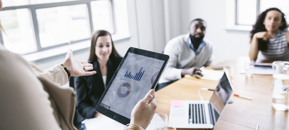 Businesswoman explaining data from tablet computer to colleagues in meeting