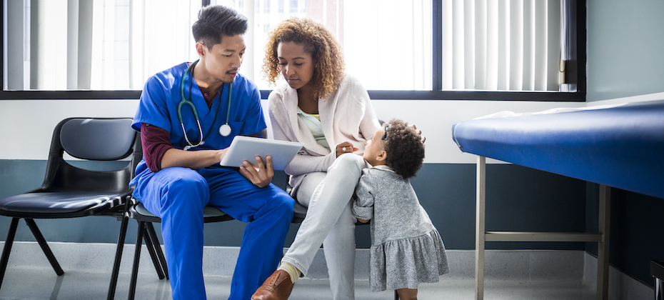 Male nurse showing digital tablet to mother by toddler in hospital