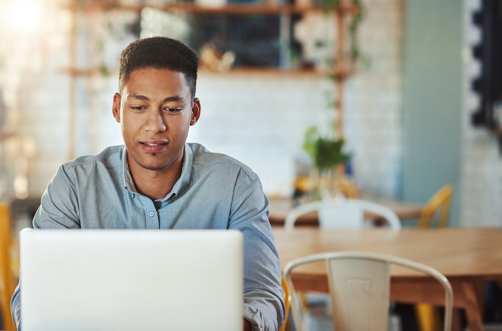 Young businessman sitting alone in a coffee shop and using his laptop