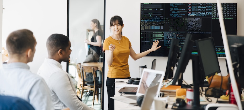 Female employee interacting with colleagues while giving presentation in office