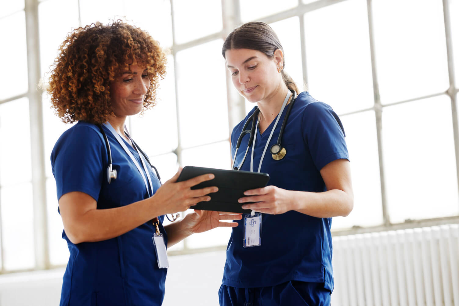 Two healthcare workers looking at a digital device.